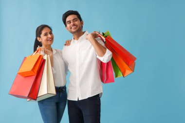 CAMERA 'nın önünde el çantalarında alışveriş torbalarıyla mutlu bir çift.
