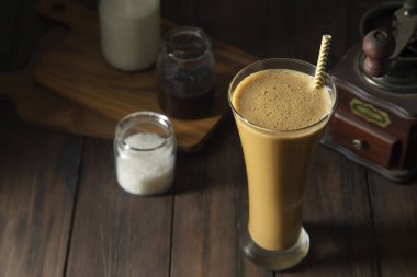 Büyük bir bardak soğuk kahve, bir kahve öğütücü ve şeker.