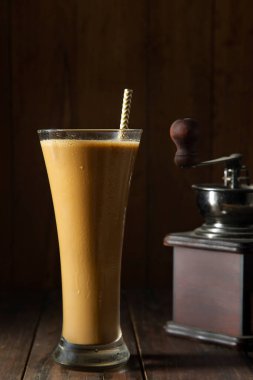 Uzun bir bardak soğuk kahve kahve kahve ve kahve çekirdeği öğütücüsü.