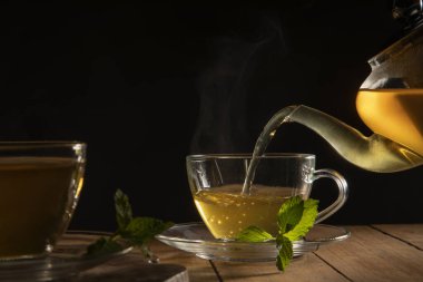 Çaydanlıktan fincana dökülen yeşil çayı kapat