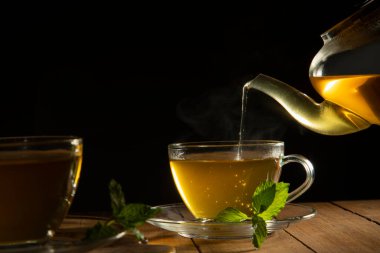 Çaydanlıktan fincana dökülen yeşil çayı kapat