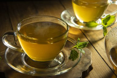 yeşil çay ve ahşap masa üzerinde nane yaprağı