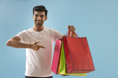 A young man pointing towards his carrybags. clipart