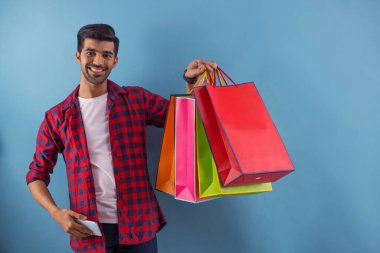 A young man standing with Carrybags and a mobile in his hands. clipart