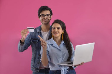 Çocuğun elindeki kartı gösteren dizüstü bilgisayarı olan bir kız..