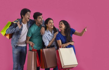 Bir kız, bir grup gencin arasında mutlu bir şekilde çantalarını taşırken başka bir yeri işaret ediyor..