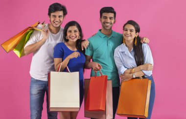 Bir grup genç, çantalarını tutarak mutlu bir şekilde duruyorlar..