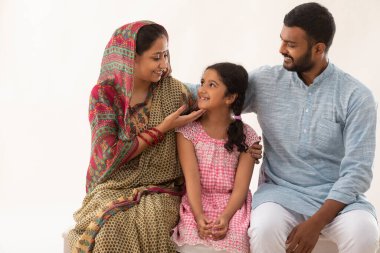 PORTRAIT OF A RURAL MOTHER SMILING AT DAUGHTER WITH FATHER BESIDES clipart