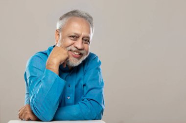 CAMERA 'ya bakan ve gülümseyen yetişkin bir adam.