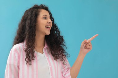 Mutlu bir ergen başka tarafa bakıyor ve parmağıyla işaret ediyor.