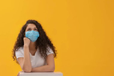 A TEENAGER WEARING FACE MASK SITTING AND THINKING clipart