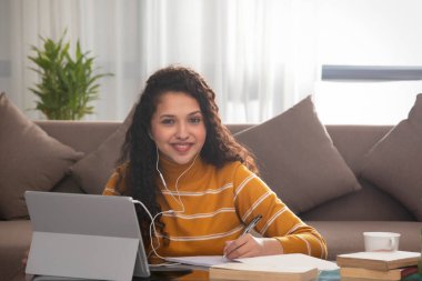 A HAPPY TEENAGER LOOKING AT CAMERA DURING ONLINE CLASS clipart