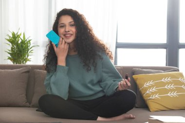 A HAPPY TEENAGER SITTING AND LOOKING AT CAMERA HOLDING LIPSTICK clipart