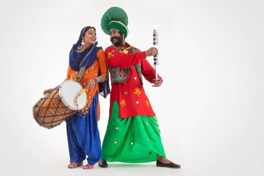 Dhol 'lu bir Giddha dansçısı ve Chimta' yla Bhangra Dansçısı birbirlerine bakıyorlar..