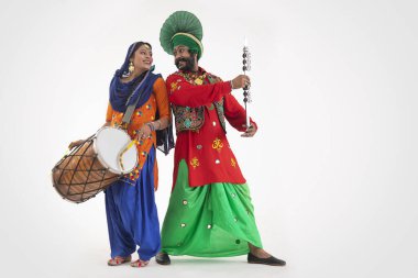 A Giddha dancer with a dhol and a Bhangra Dancer with Chimta looking at each other. clipart