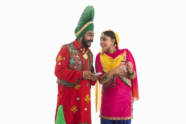 A Bhangra and A Giddha Dancer discussing biils having a mobile and credit card in hand. clipart