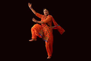 A woman in Giddha costume depicting a dance step with hands and a leg in the air. clipart