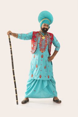 A Bhangra dancer holding a Khunda in his hand. clipart