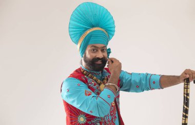 Bir Bhangra Dansçısı elinde bir Khunda ile sakalını okşuyor..