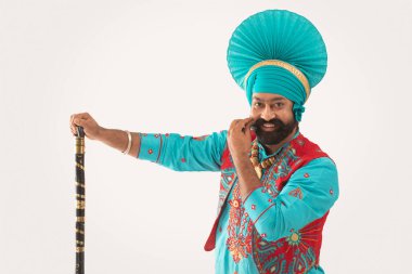 Bir Bhangra Dansçısı elinde bir Khunda ile sakalını okşuyor..