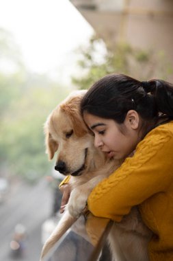 Genç bir kız ve evcil köpek Rail 'e doğru eğiliyor ve aşağı bakıyor.