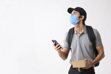 Teslimatçı çocuk bir elinde cep telefonuyla, diğer elinde bir paketle yukarı bakıyor.