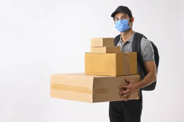 Paketleri elinde tutan maske takan teslimatçı çocuk.