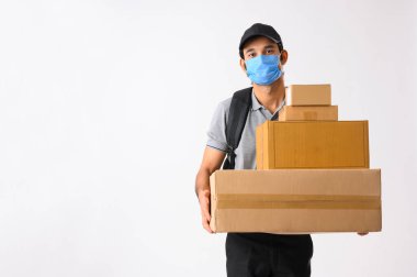 Paketleri elinde tutan maske takan teslimatçı çocuk.
