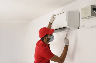 Teknisyen, kontrol etmek için klimayı tornavidayla açıyor.