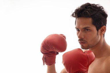 Boks eldiveni giyen ve beyaz bir arka planın önünde duran bir adam.
