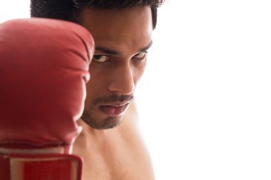 Beyaz bir arka plan üzerinde çıplak duran boks eldiveni giyen bir adam.