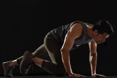 Koyu bir arkaplan önünde egzersiz yapan adam