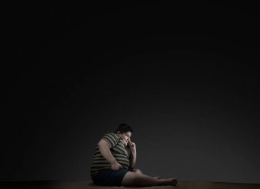 Genç çocuk yerde oturuyor ve televizyon izliyor (Obezite)