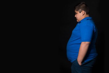 Young boy standing sideways with his hands in his pockets(Obesity)