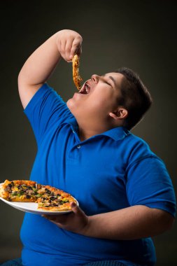 Küçük çocuk bir dilim pizza yiyor.)