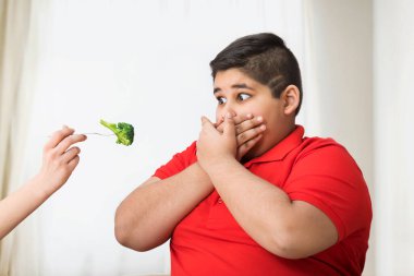 Ağzını brokoliden uzak tutan genç bir çocuk.)