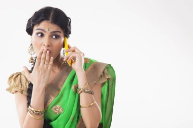 Telefonda bazı dedikodular duyan genç bir kadın şaşırmış görünüyor. (Ev hanımı)