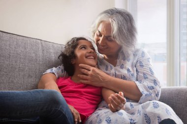 Evde kanepede oturan bir torun ve büyükannenin portresi..