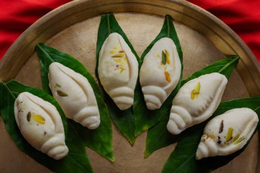 Shankh biçimli sondesh yaprakların üzerinde güzelce düzenlenmiş..