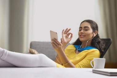 Bekar bir kadın elinde telefonuyla müzik dinliyor..