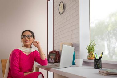 Single woman sitting in her office in front of her laptop. clipart