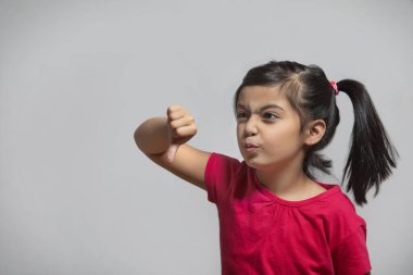 Genç kız baş parmağını aşağı gösteriyor ve surat yapıyor.