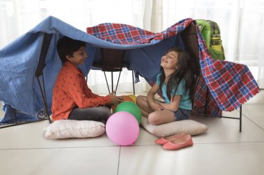 Abi ve kız kardeş evde kamp yapıyor.