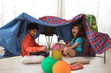 Abi ve kız kardeş evde kamp yapıyor.