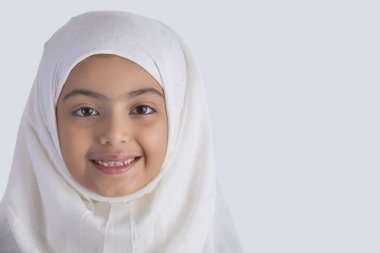 Genç Müslüman kız tesettürlü ve gülümsüyor.