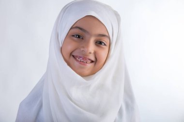Genç Müslüman kız tesettürlü ve yüzü eğik gülümsüyor.