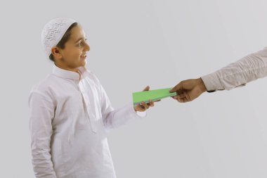 young muslim boy wearing cap receiving eidi on the occasion of eid clipart