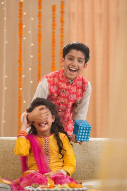 Brother surprising her cute little sister with a Gift pack on Rakshabandhan clipart