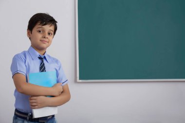 Okul çocuğu elinde bir kitapla tahtaya çıktı.