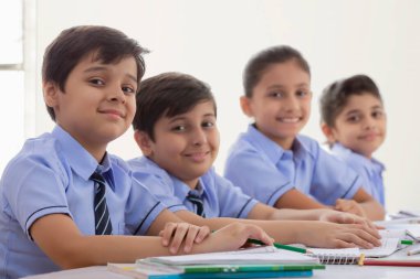 Çocuklar sınıfta çalışıyor ve gülümsüyor.